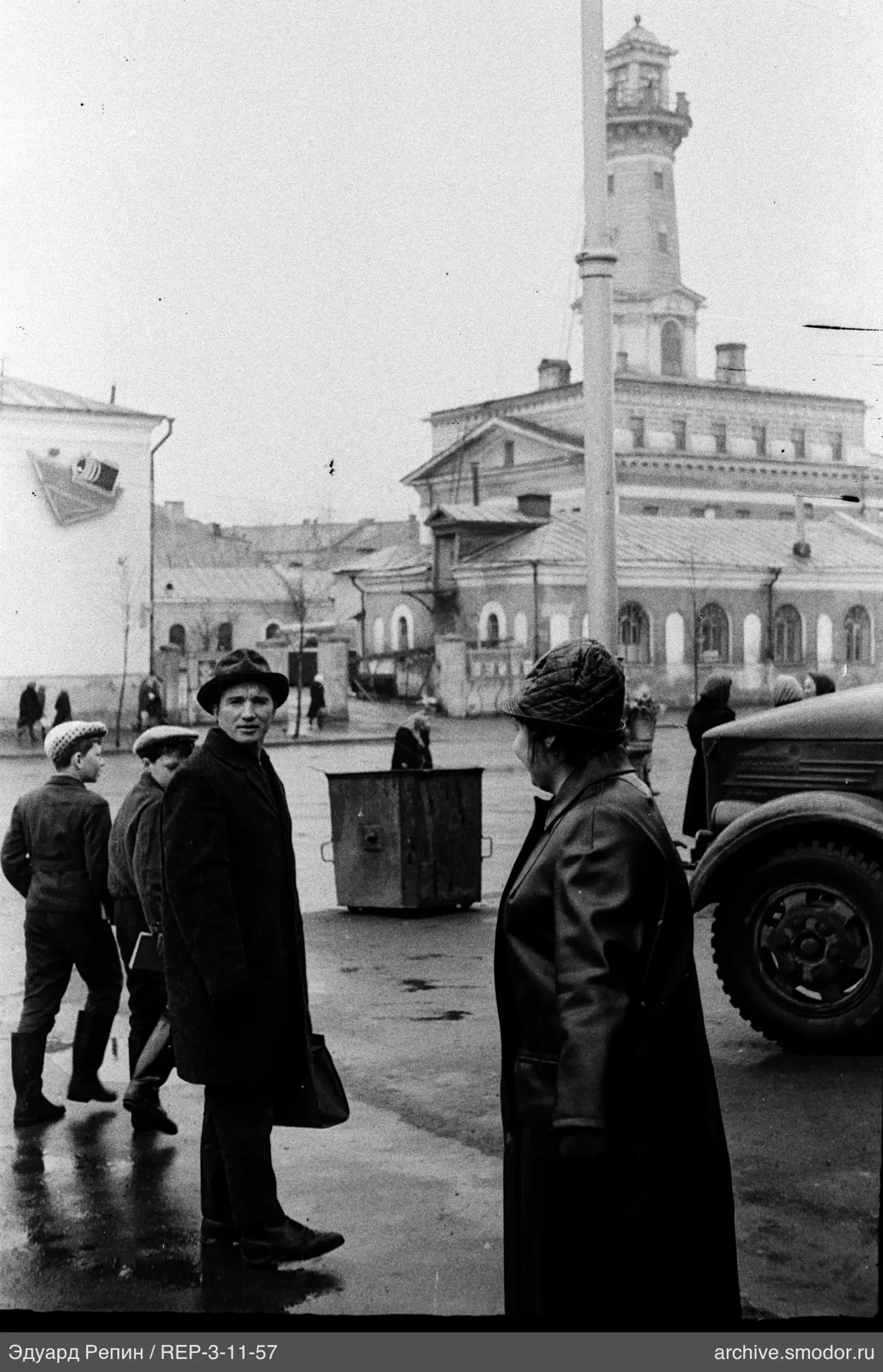 Группа людей на улице с зданиями и автомобилем