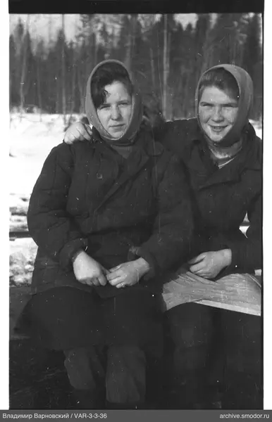 Two women sitting on a bench in winter landscape