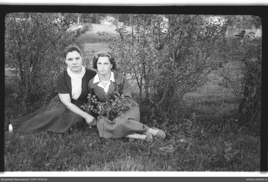 Zwei Frauen auf dem Gras bei Büschen
