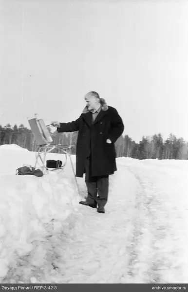 Mann malt auf einer Staffelei im Schnee