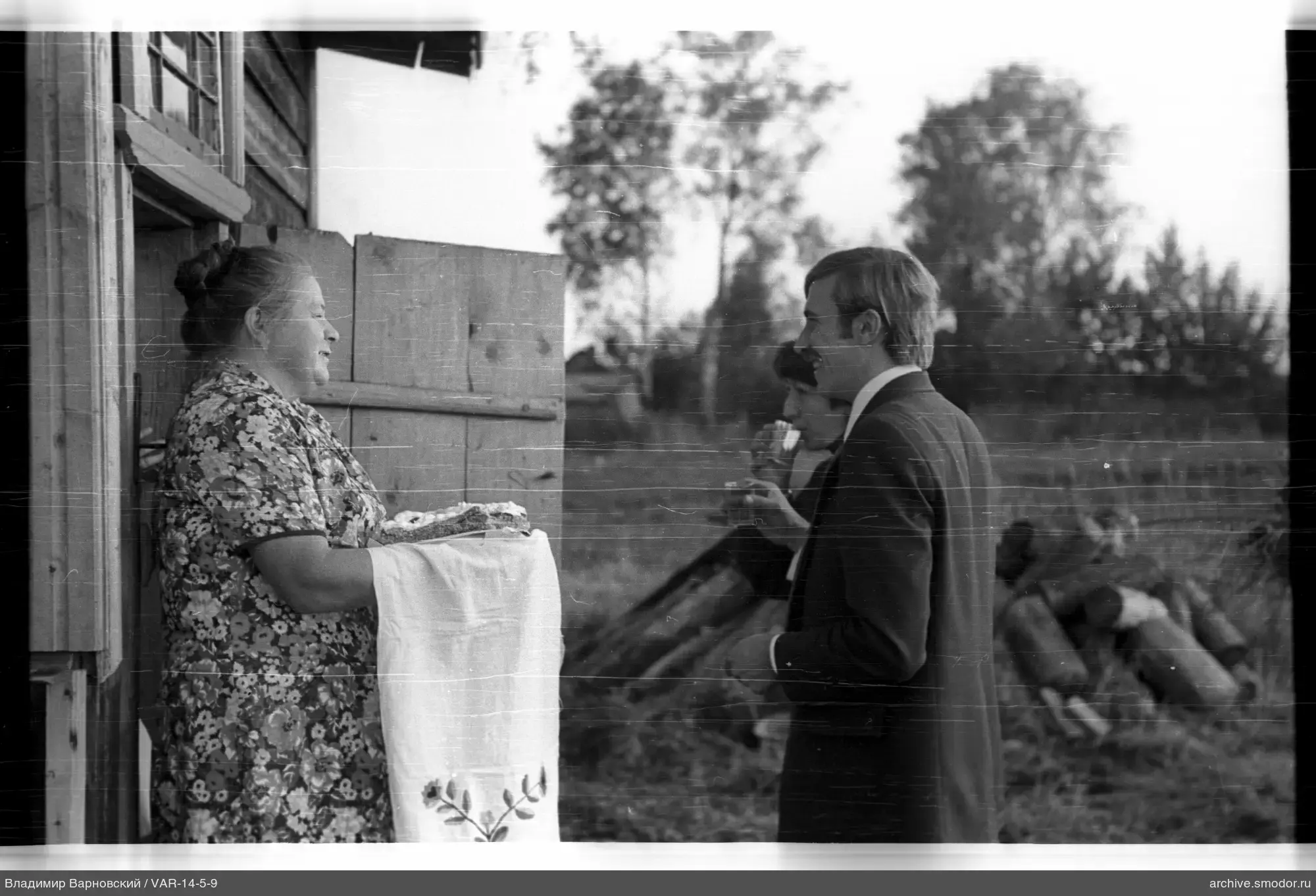 Frau mit Brot vor Holzhaus