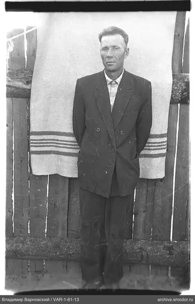 Man with hands behind back by wooden fence