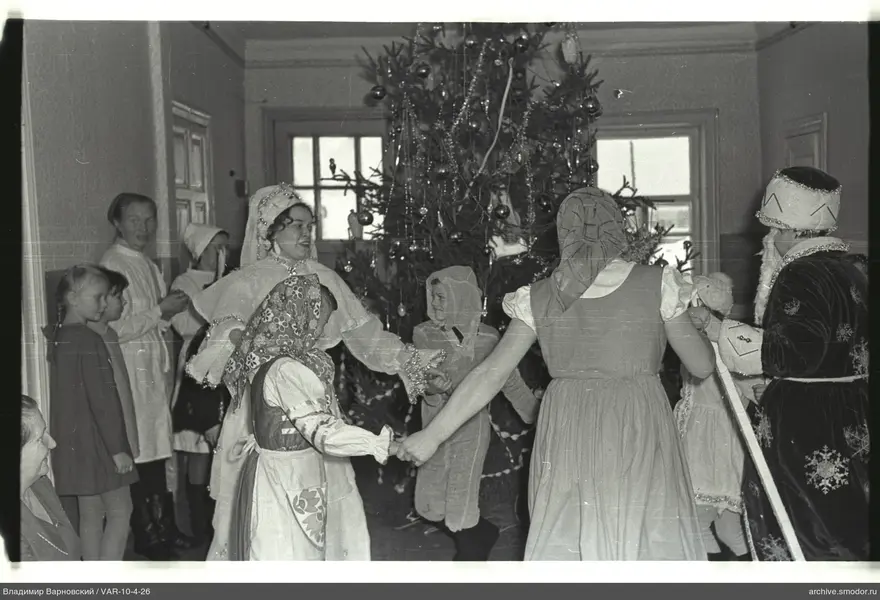 Kinder und Erwachsene um geschmückten Weihnachtsbaum