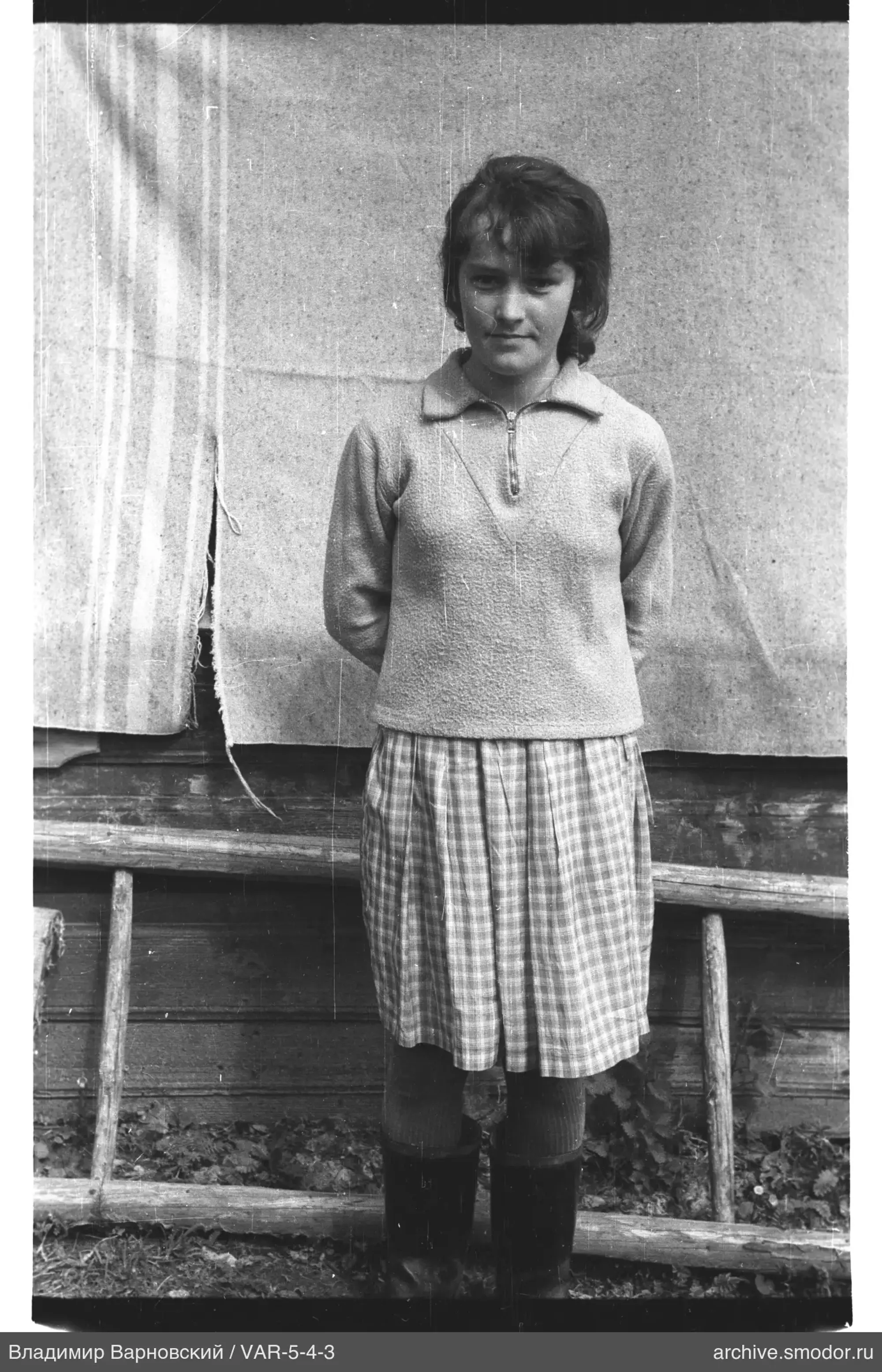 Woman with hands behind back by wooden wall
