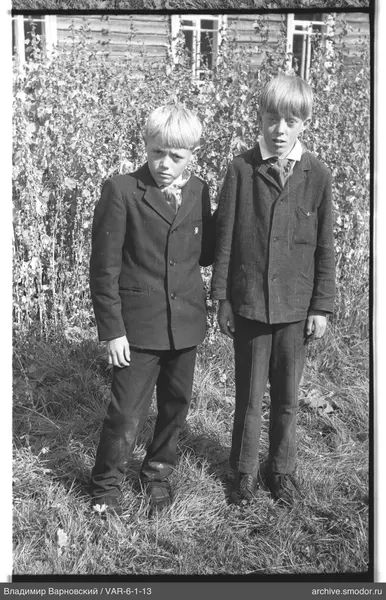 Zwei Jungen in dunklen Anzügen auf dem Gras