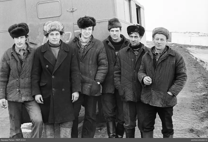Группа мужчин у металлического фургона
