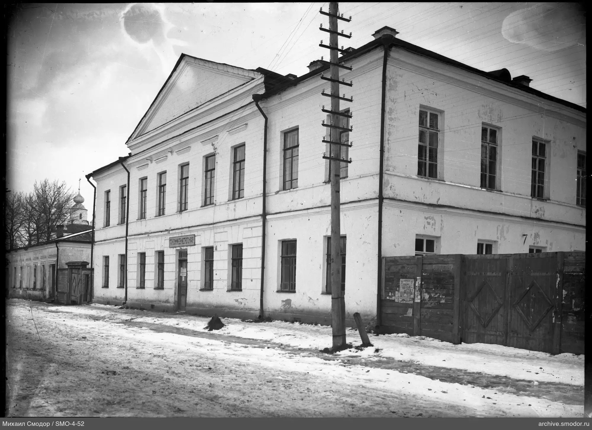 Двухэтажное здание с вывеской и церковью