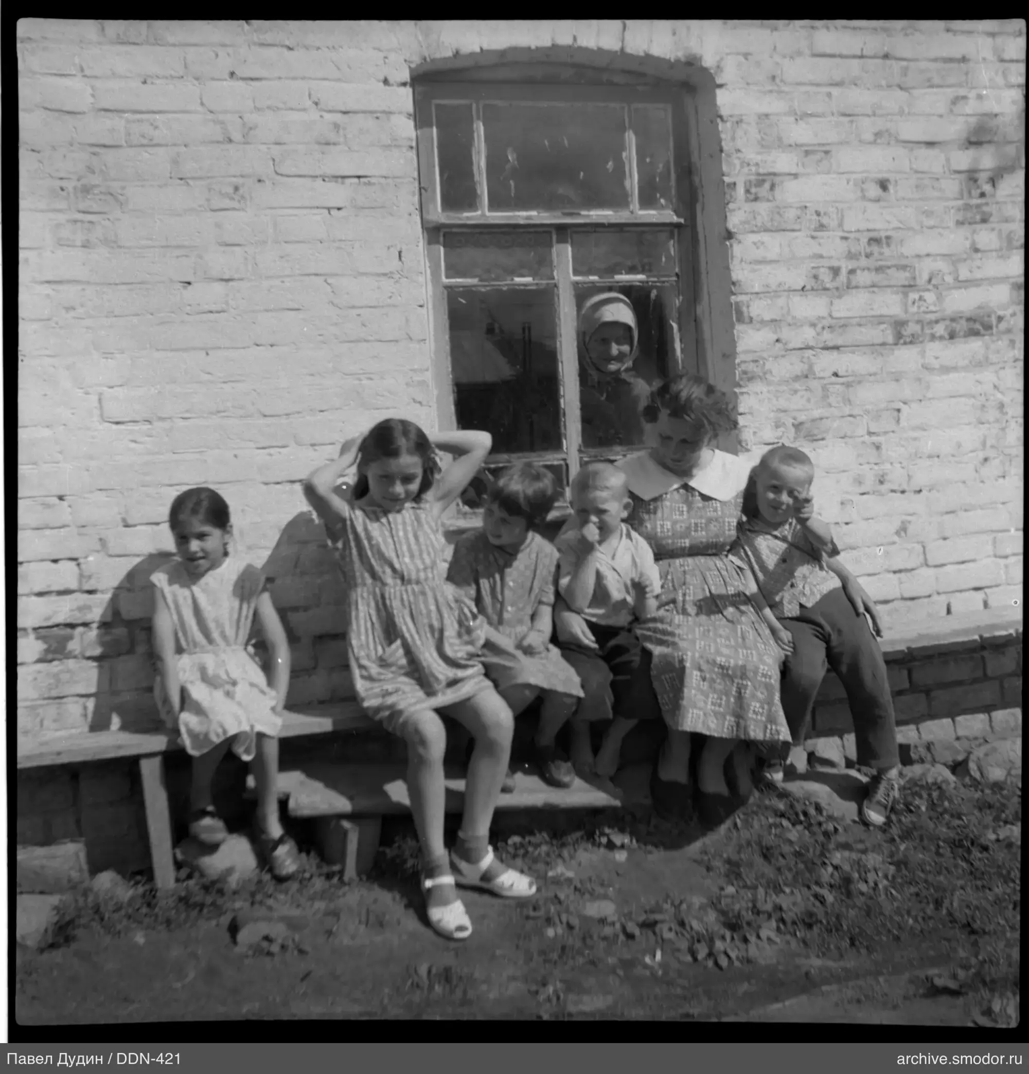 Gruppe von Kindern und Frau an Ziegelwand