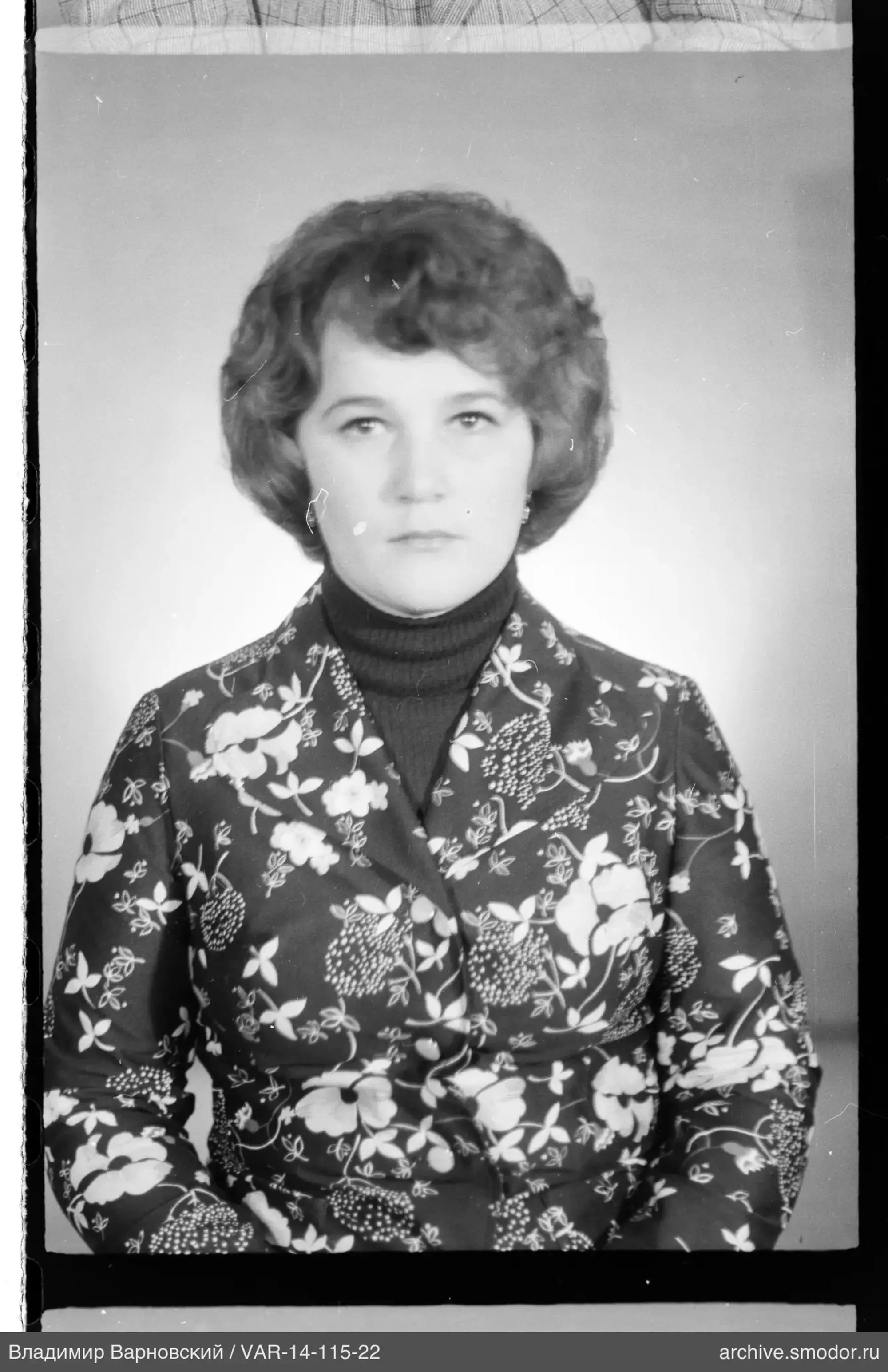 Porträt einer Frau in dunklem Rollkragenpullover und Blumenjacke