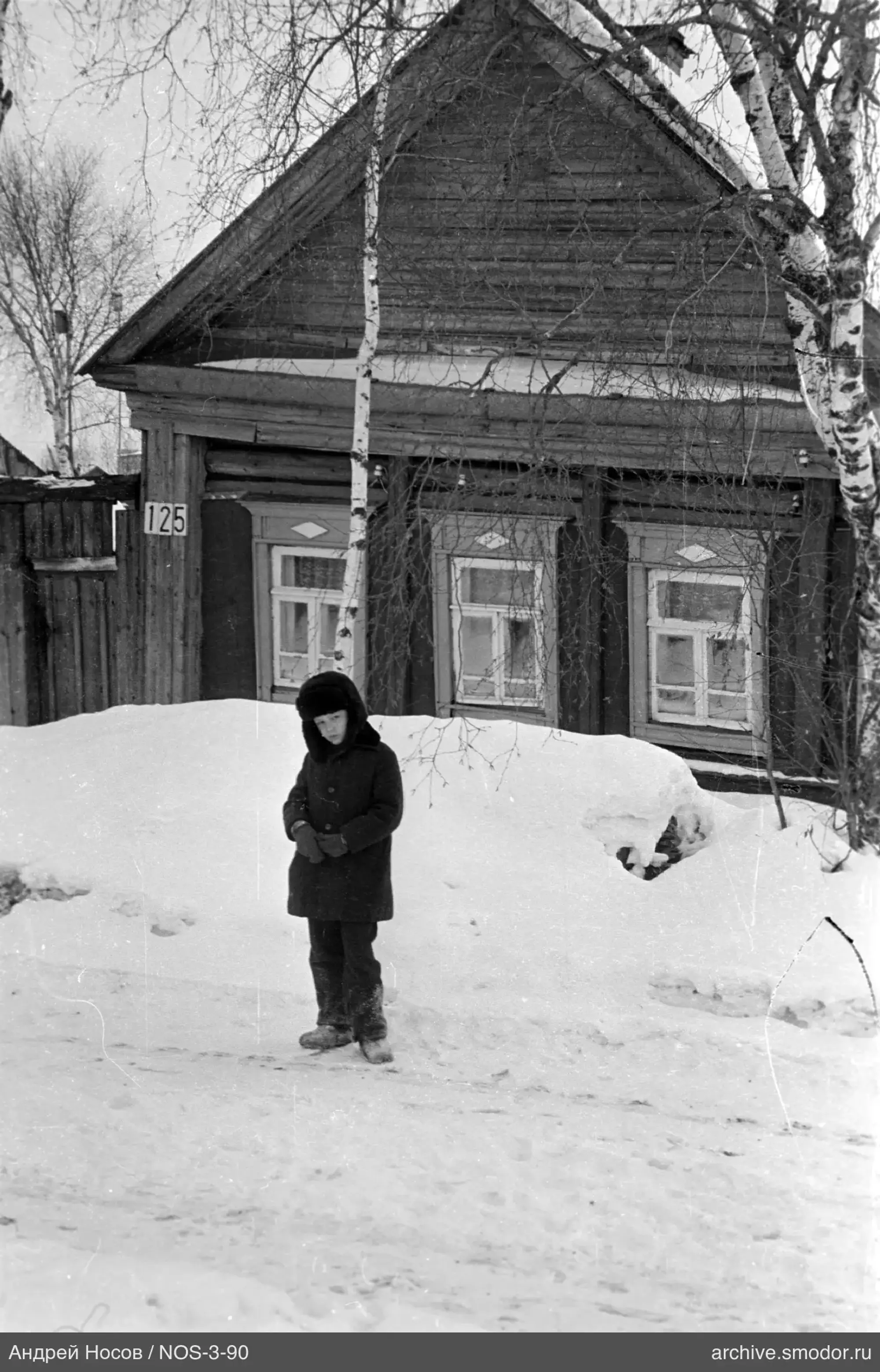 Ребёнок на заснеженной улице у дома