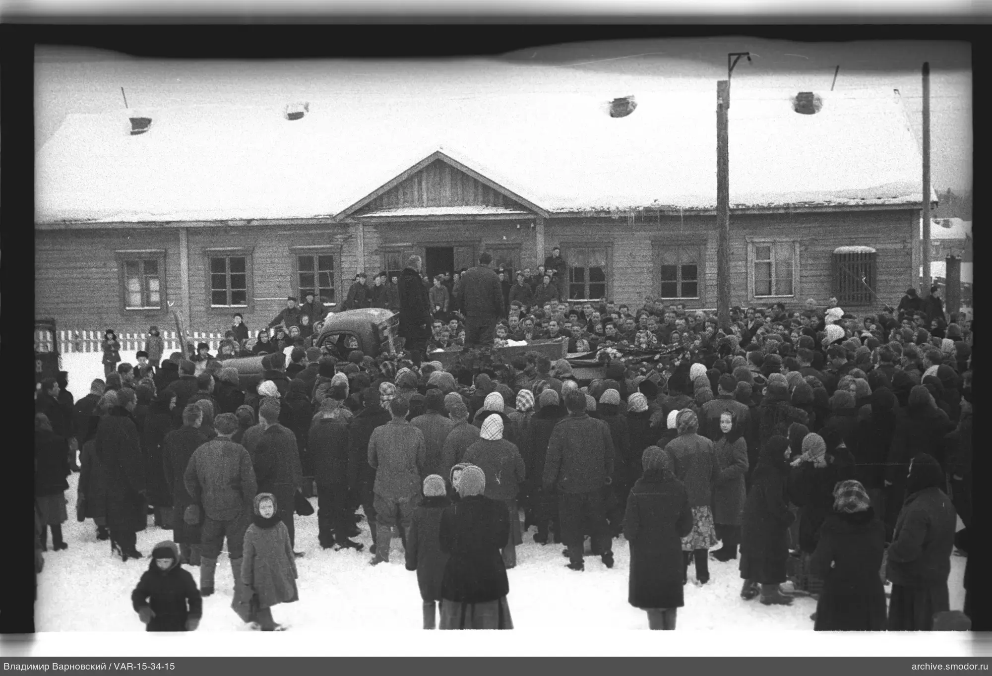 Группа людей у деревянного здания на снегу