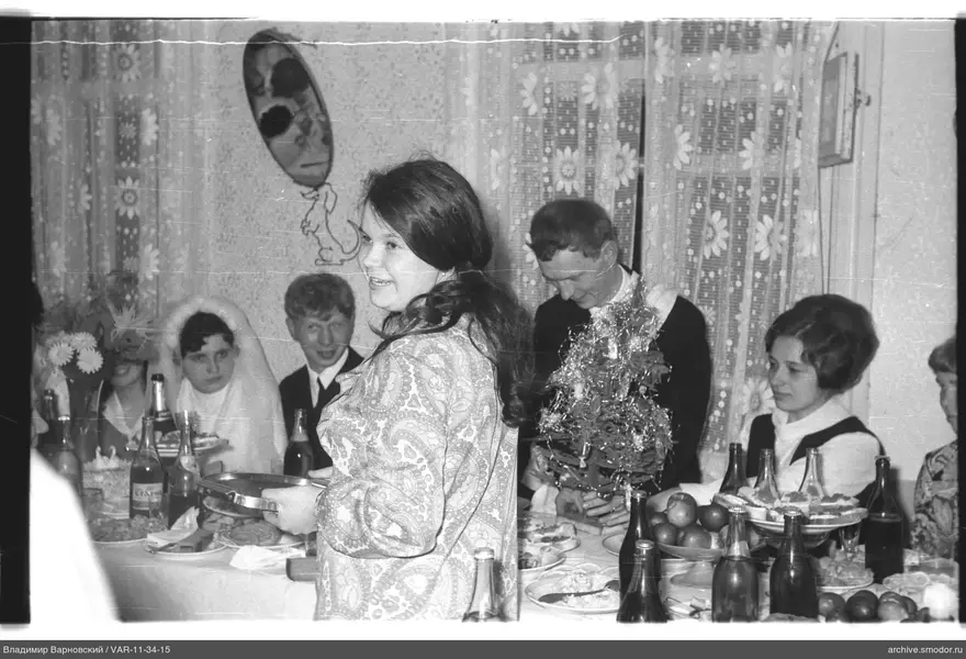 Женщина с подносом у стола с гостями