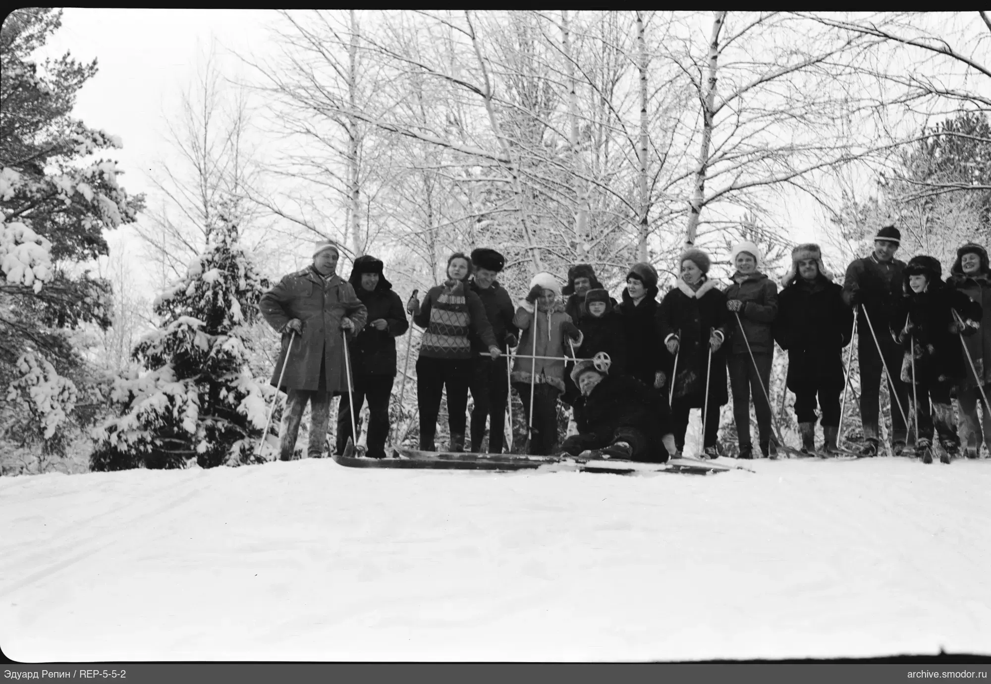 Gruppe von Menschen im Schnee mit Skiern und Bäumen