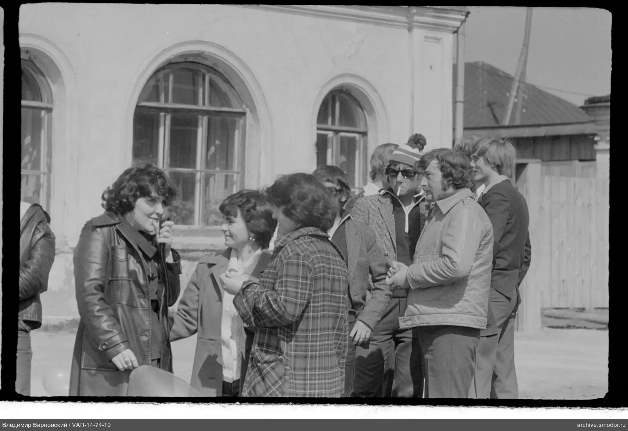 Gruppe von Männern und Frauen vor Bogenfenstern
