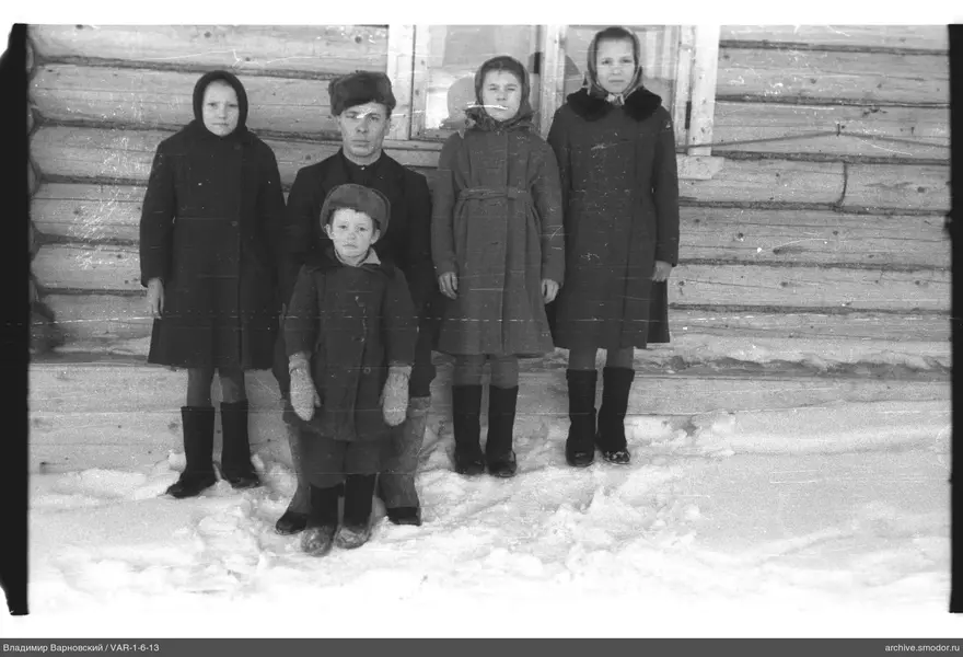 Gruppe von Menschen im Schnee vor einem Holzhaus
