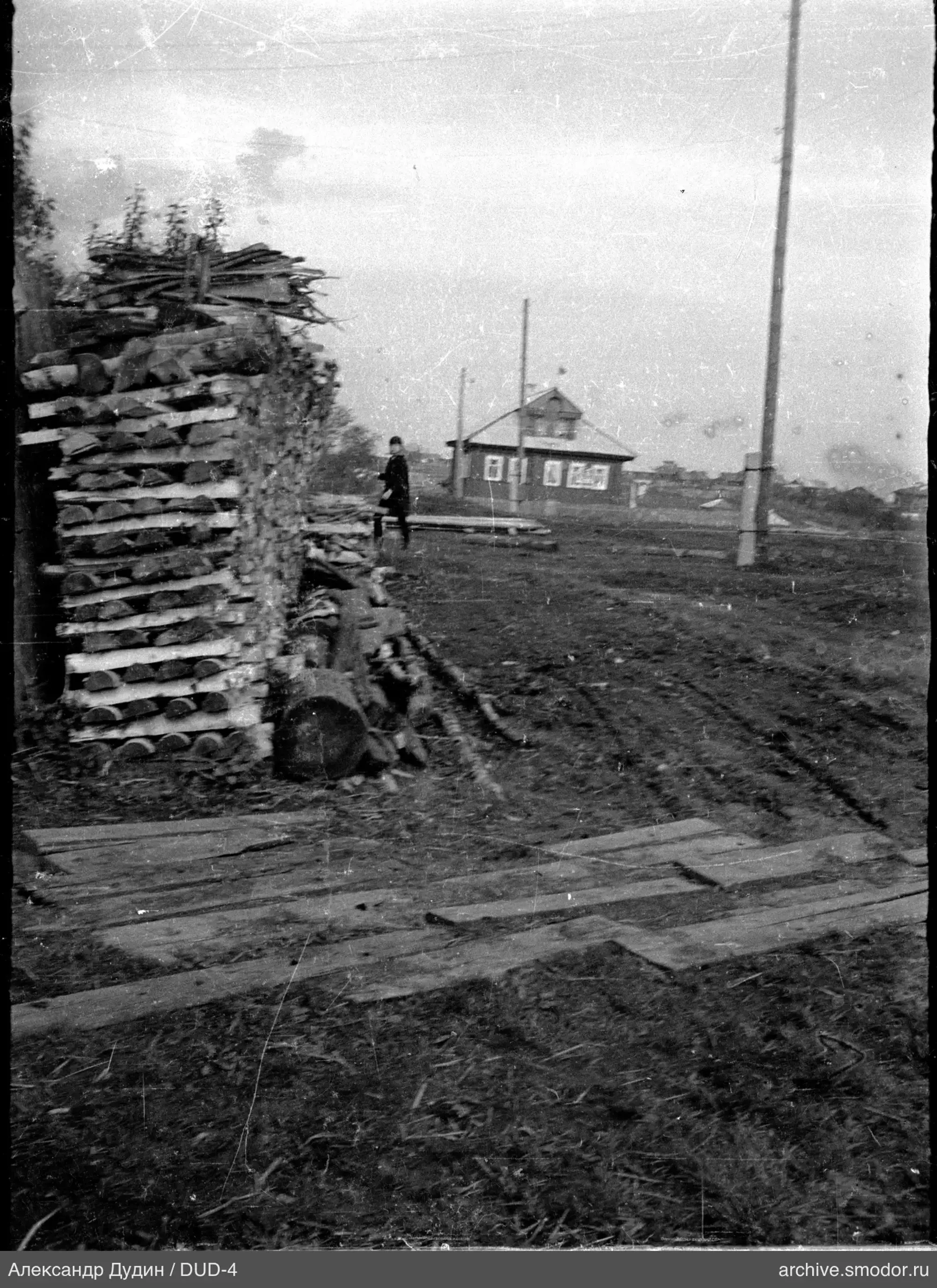 Stacks of firewood and a person by a wooden house