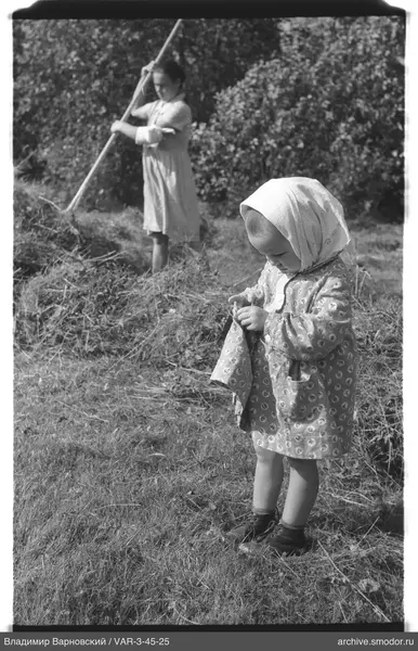 Girl and woman with pitchfork near bushes