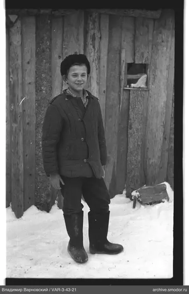 Junge auf Schnee bei Holzwand