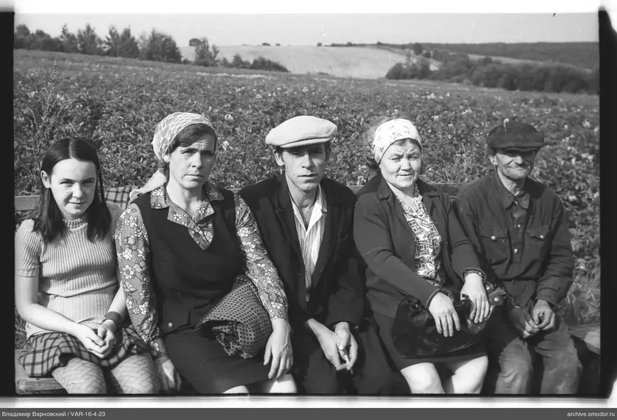 Gruppe von Menschen auf einer Bank vor einem Feld