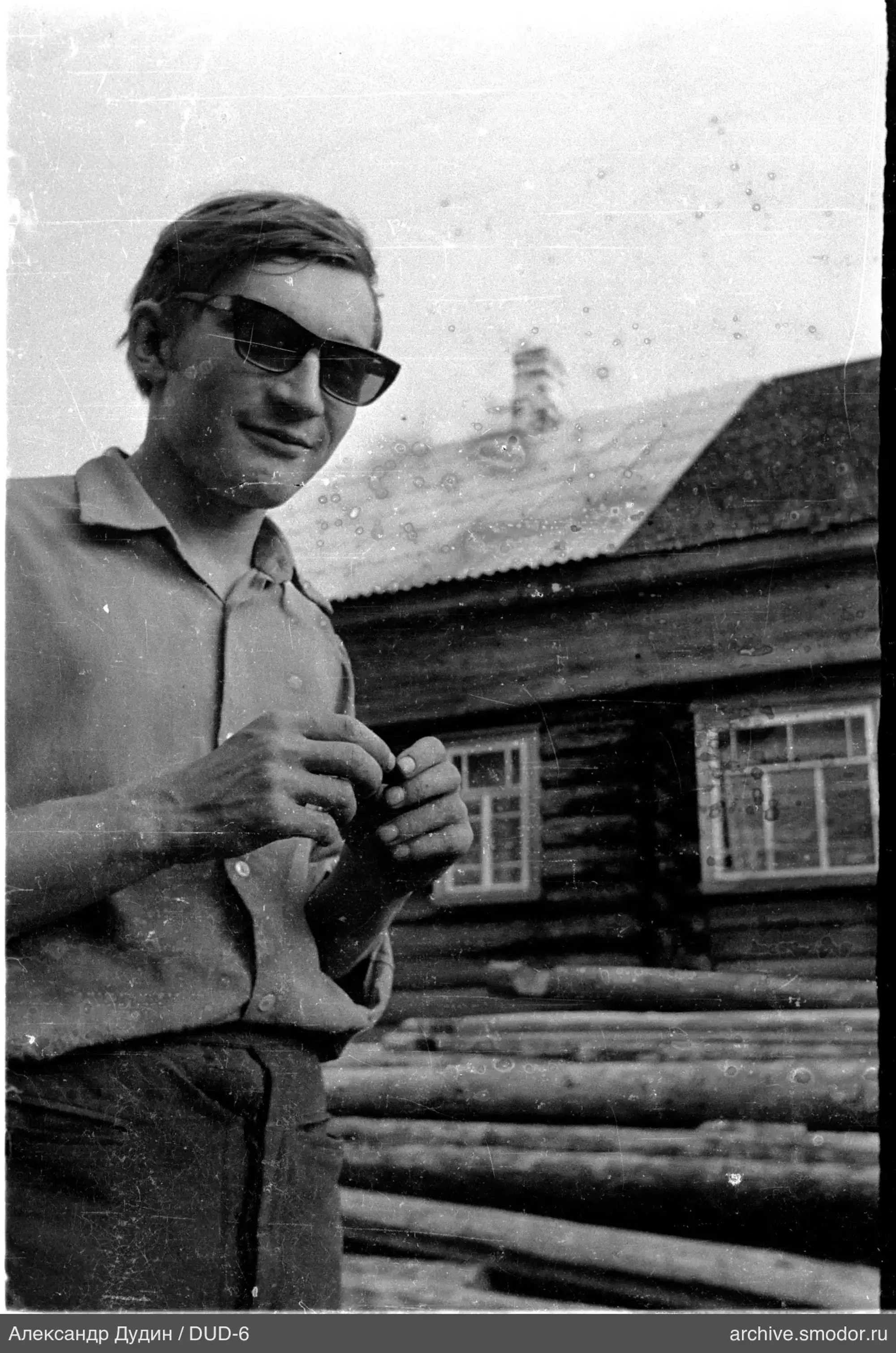 Mann mit Brille vor einem Holzgebäude