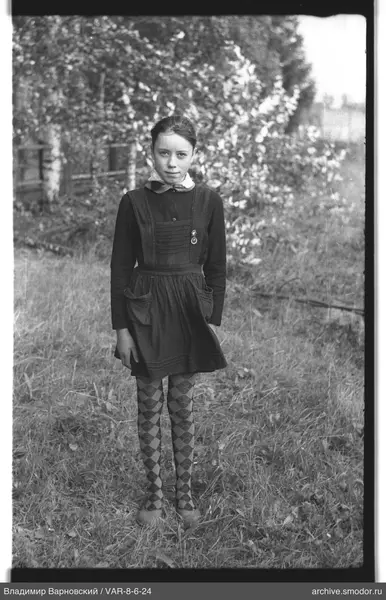 Mädchen im Kleid mit Schürze auf Gras