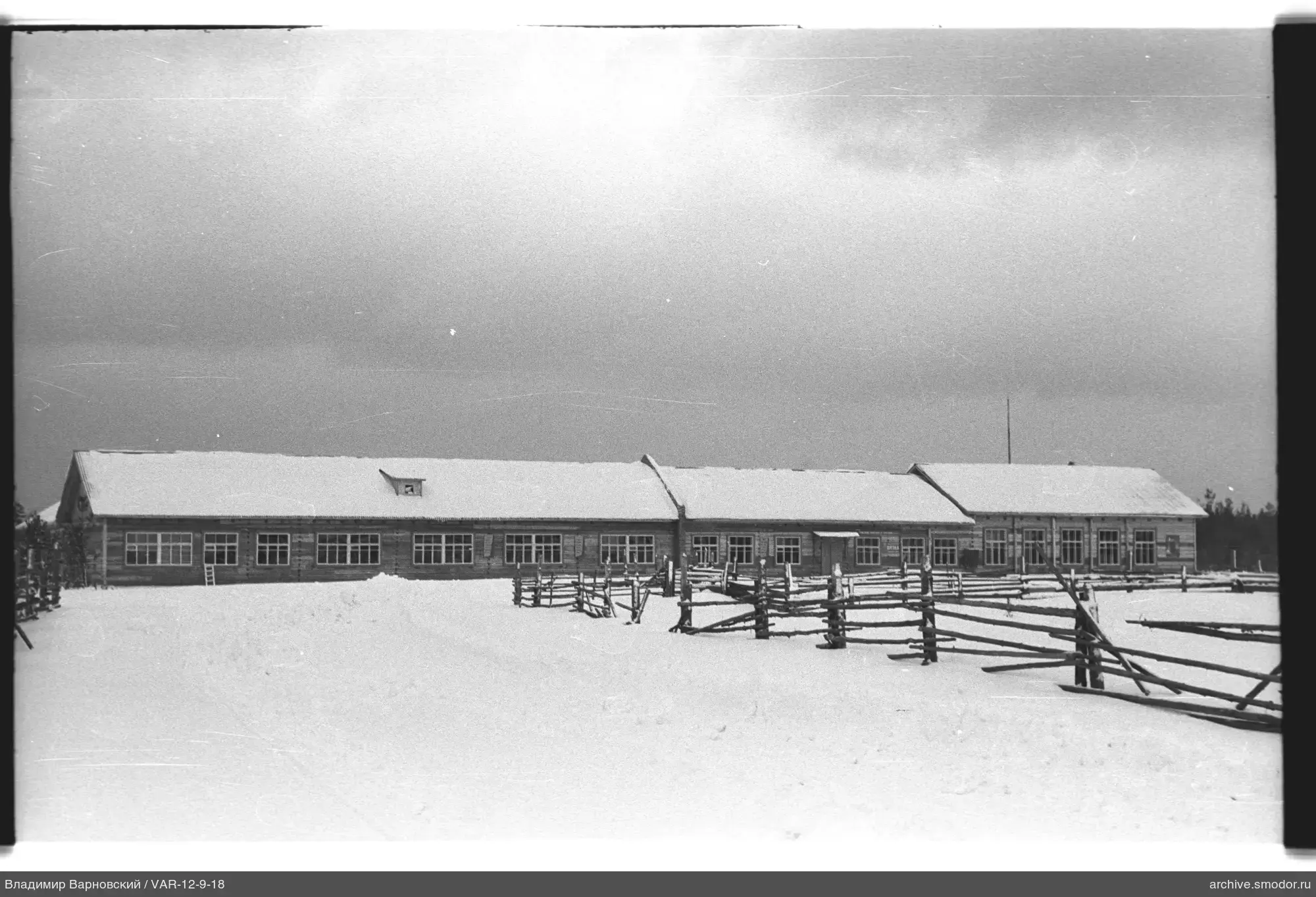 Holzgebäude mit Zaun und Schnee