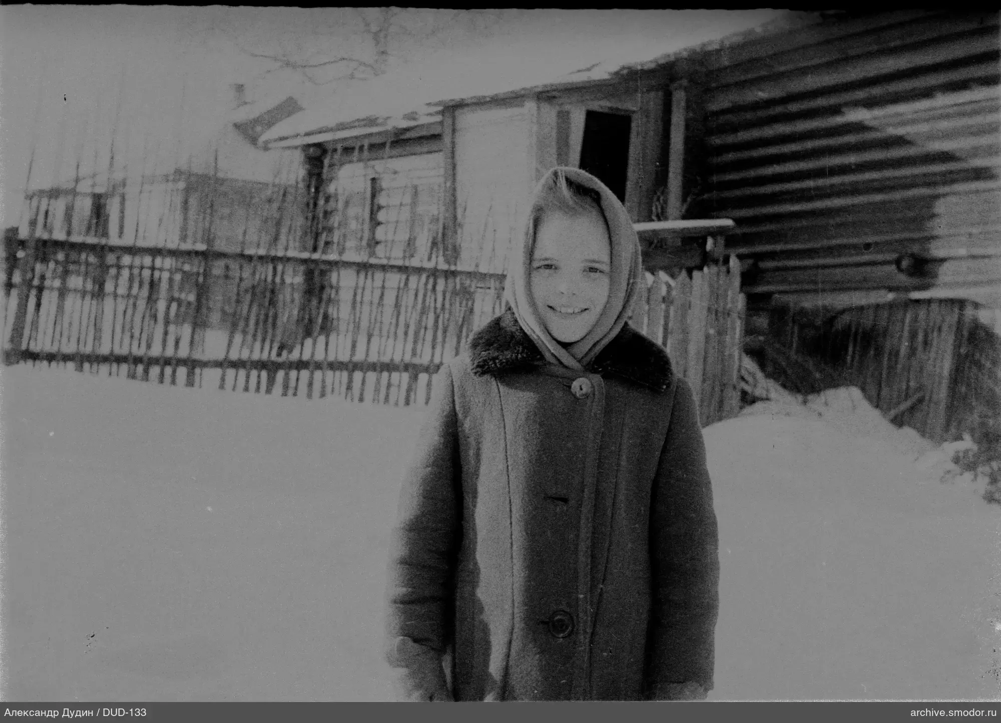 Mädchen im Schnee vor einem Holzhaus