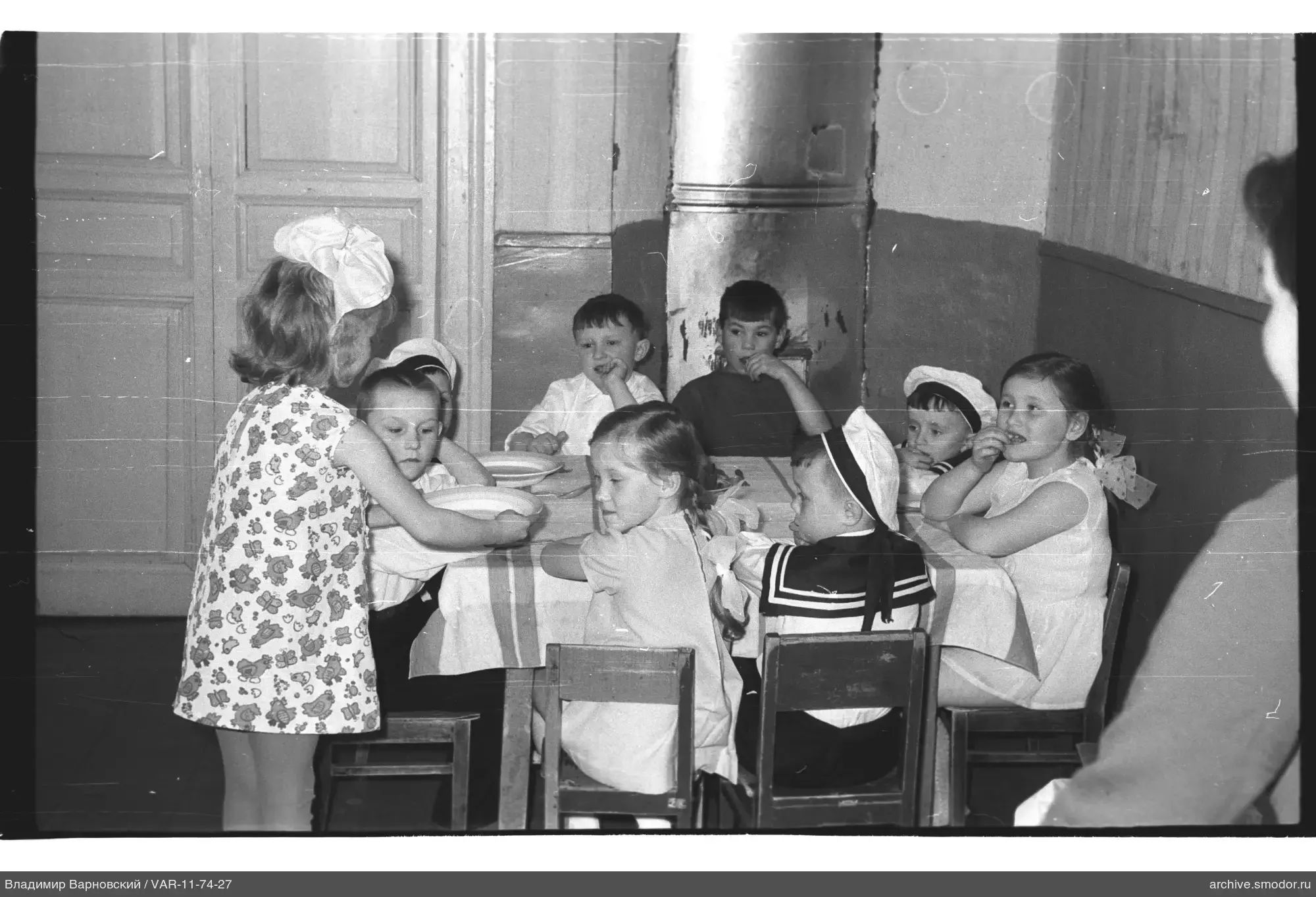 Kinder am Tisch mit Tellern und Erwachsener