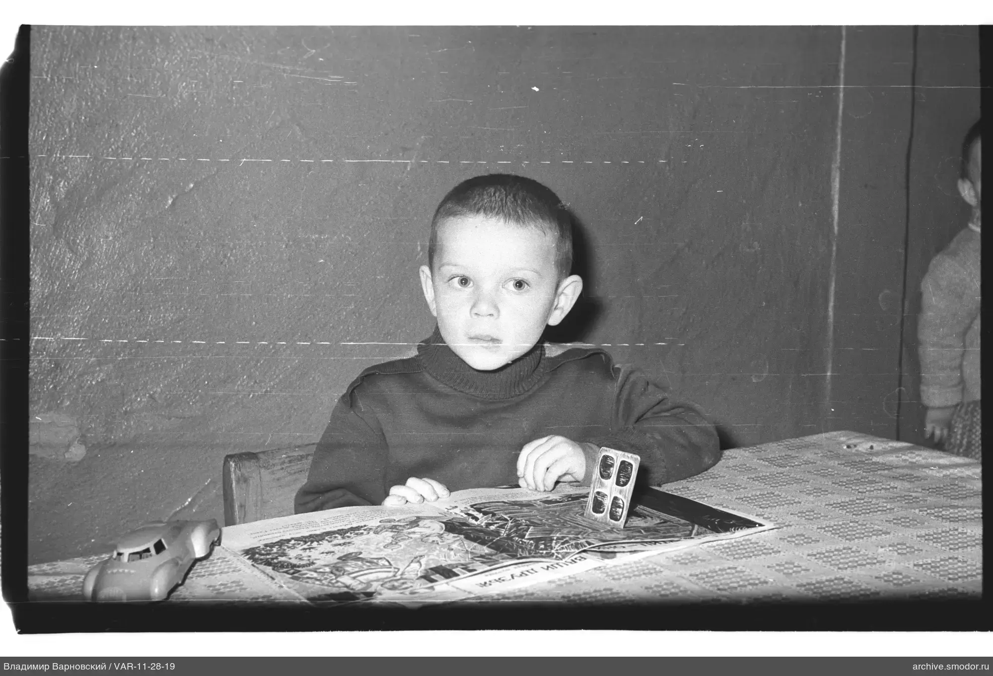 Kind am Tisch mit Buch und Spielzeugauto