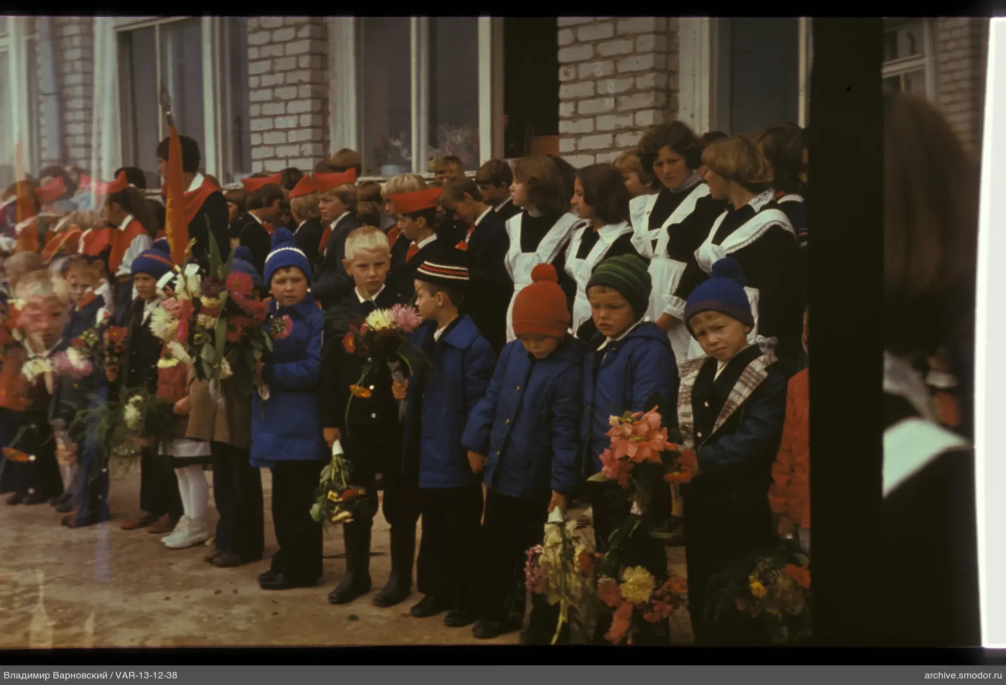 Group of children and teenagers with bouquets in school uniforms