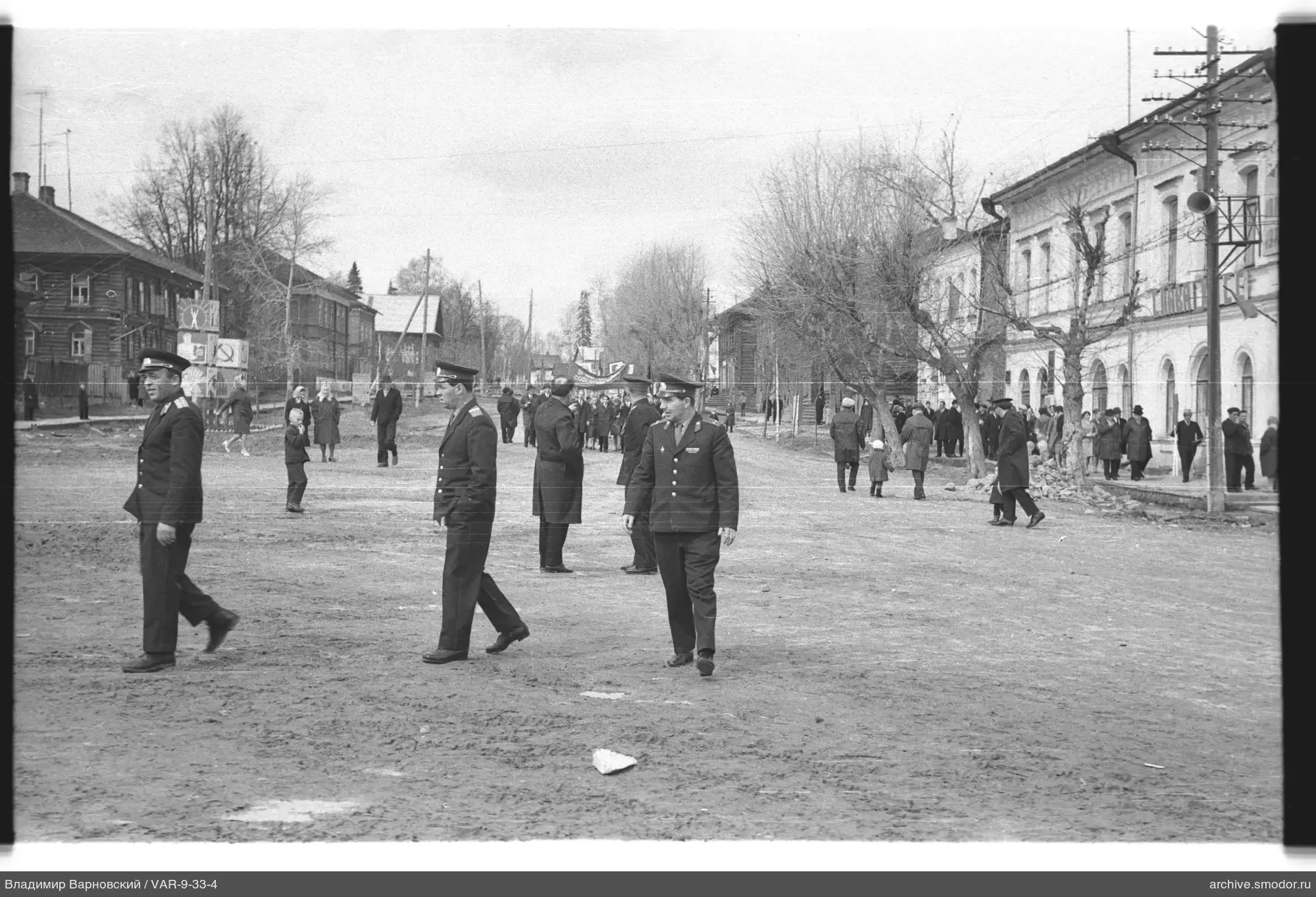 Men in uniform on street with group of people