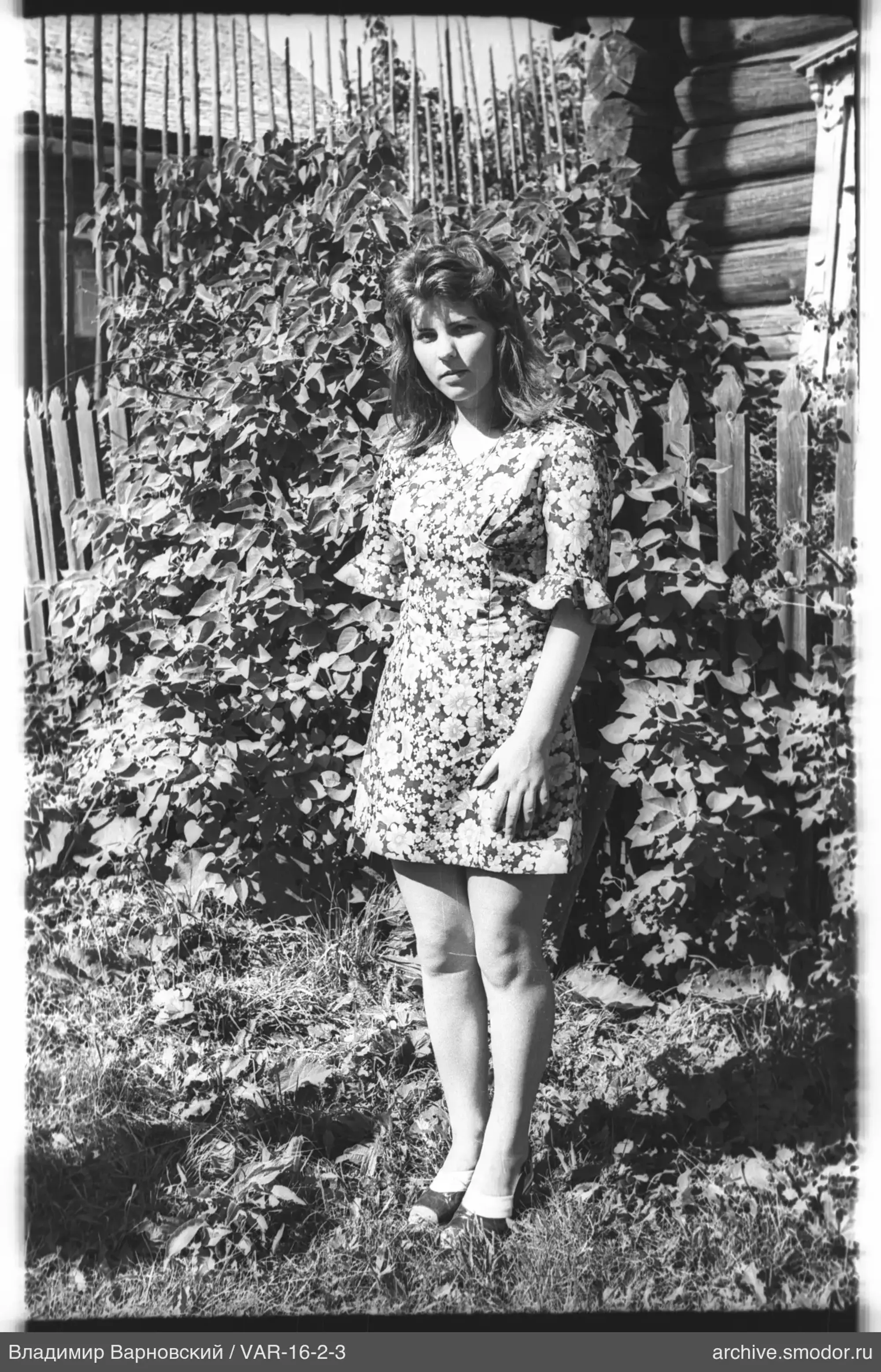 Frau neben Holzzaun und Haus