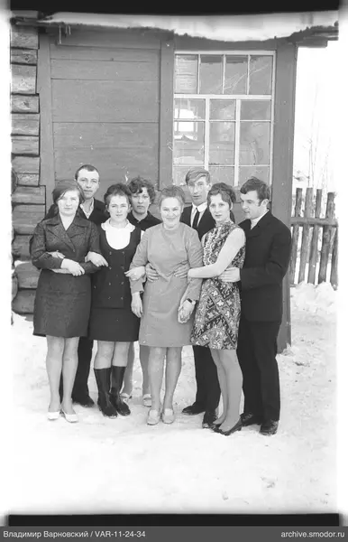 Gruppe von Menschen vor Holzgebäude im Schnee