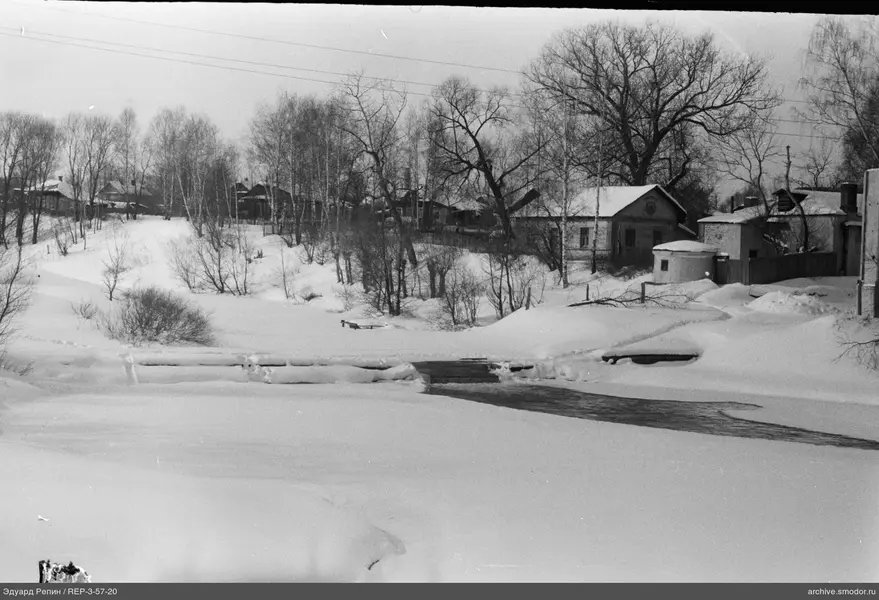 Schneebedeckte Landschaft mit Häusern und Brücke