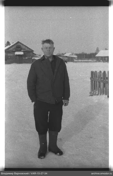 Мужчина на снегу у деревянных домов