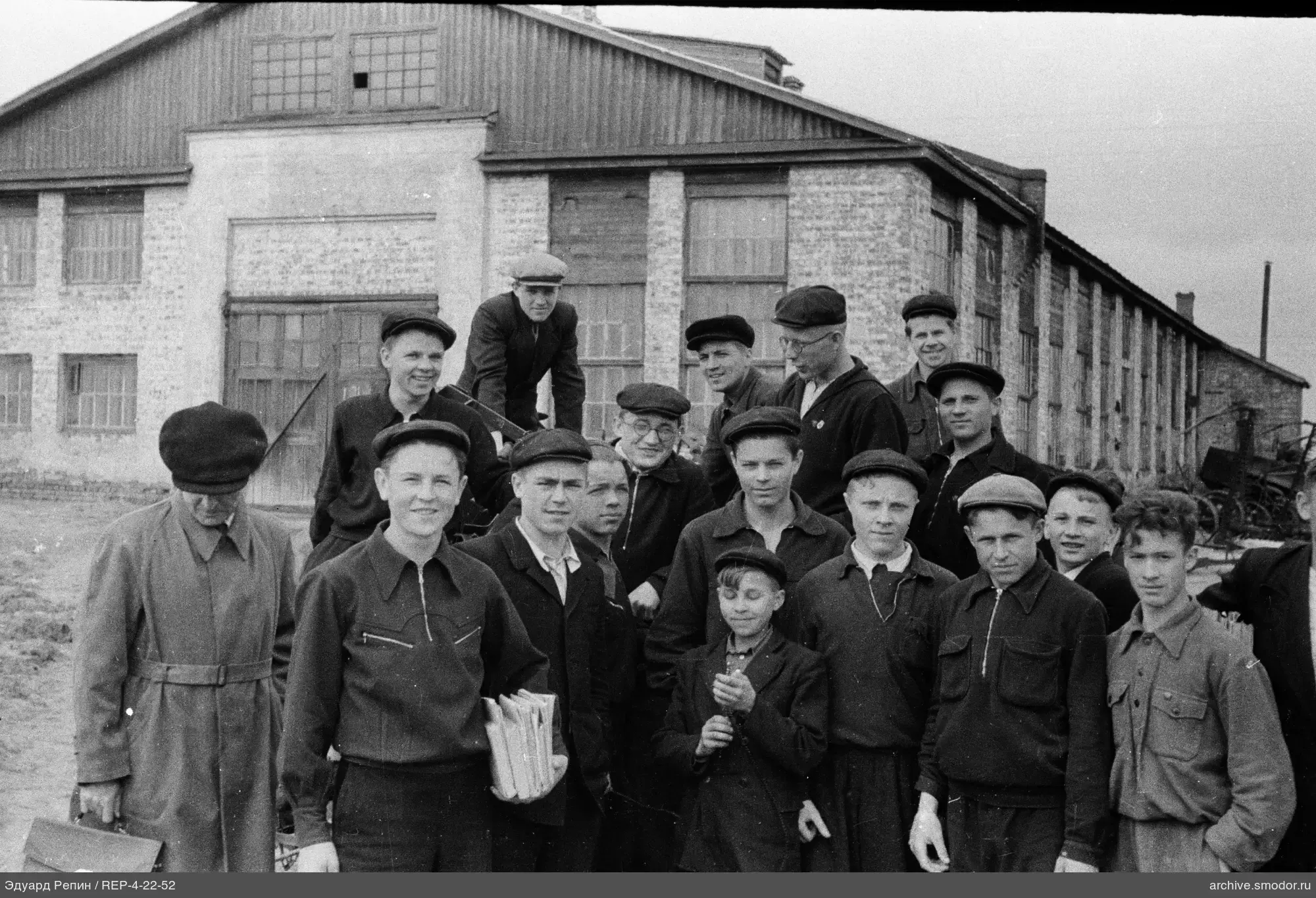 Gruppe von Männern und Jungen vor Backsteingebäude