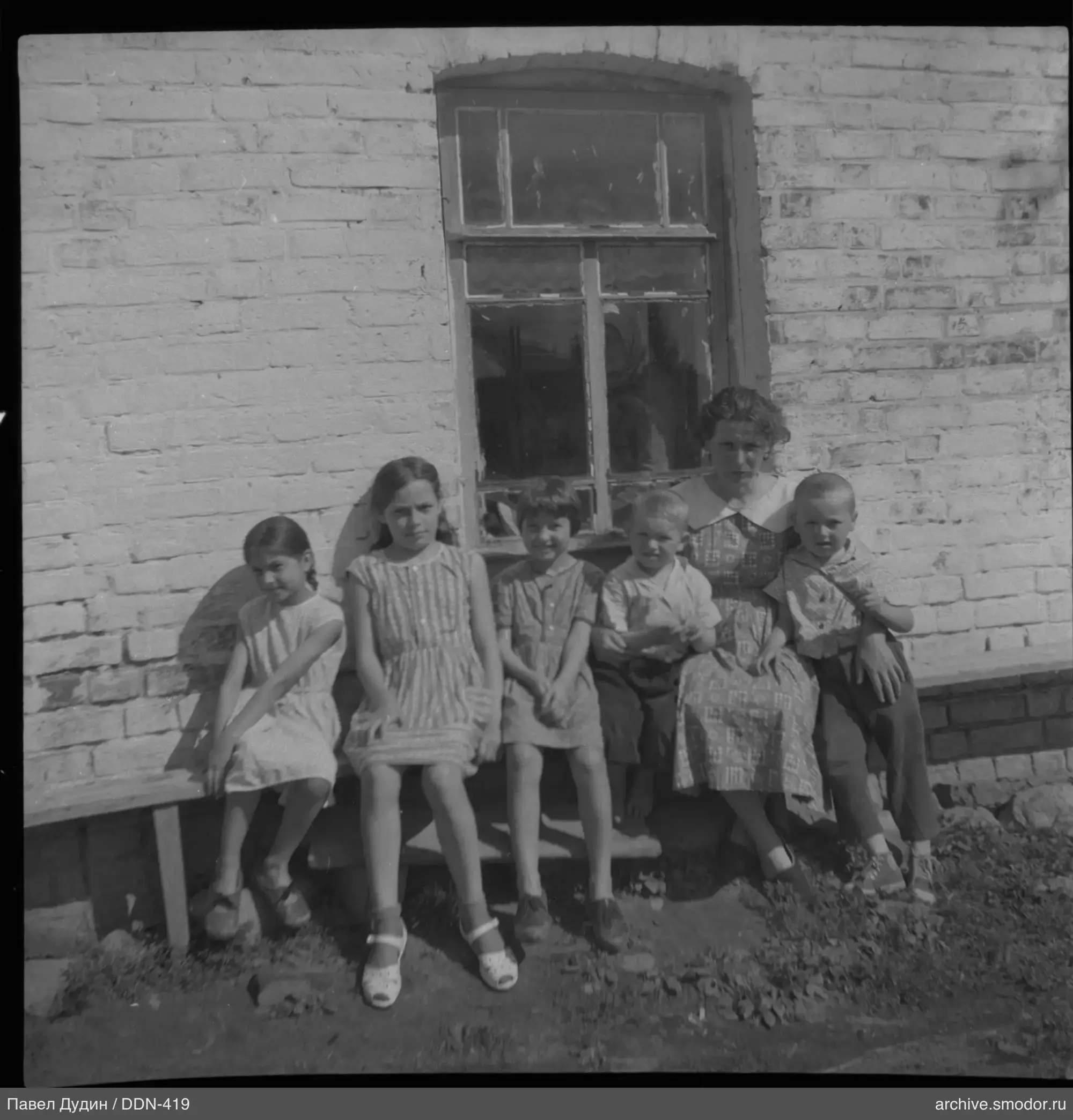 Gruppe von Kindern und Frau auf Bank