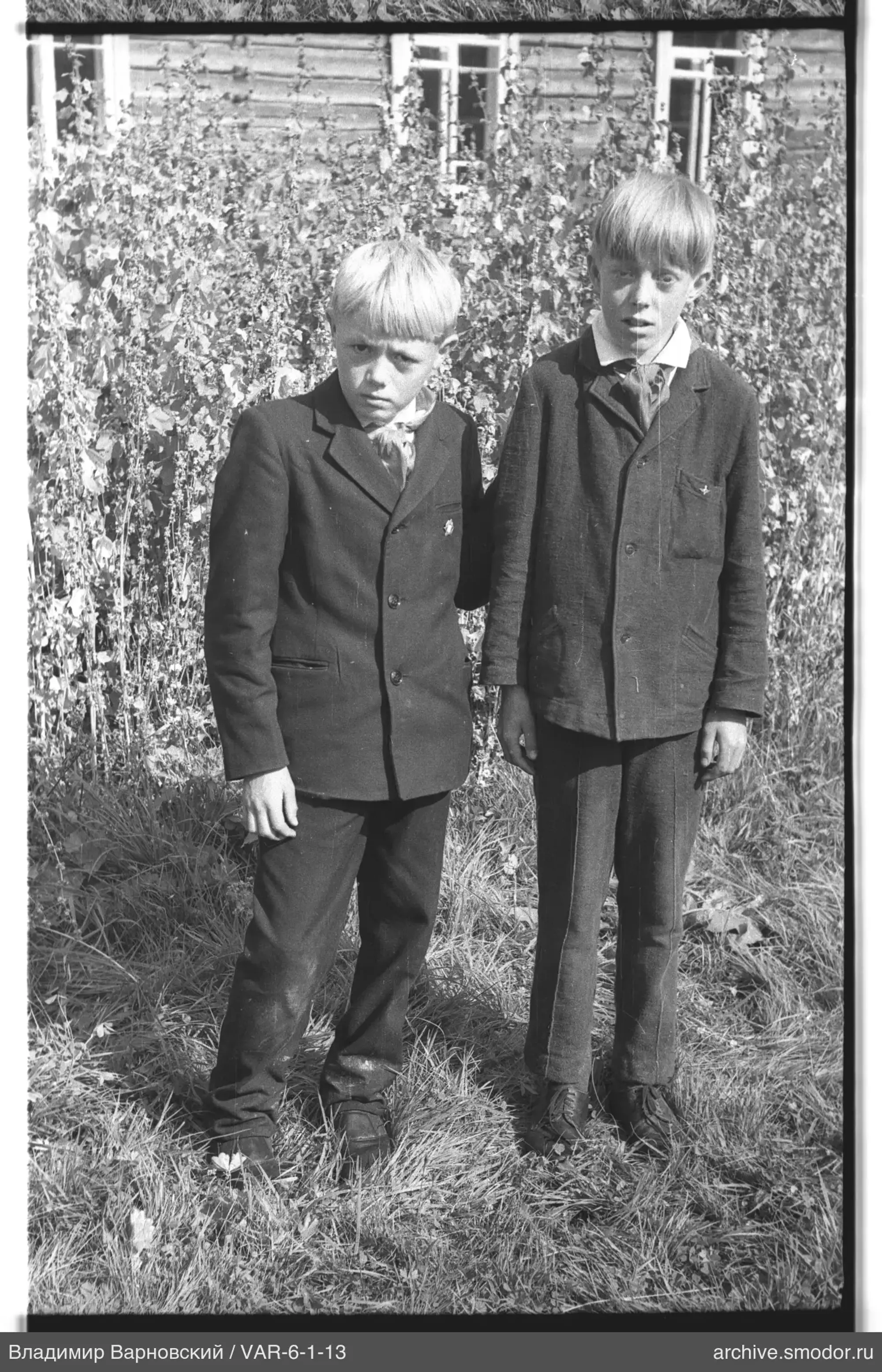 Two boys in dark suits on the grass