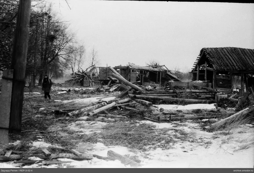 Zerstörte Holzbauten und eine Person auf der Straße