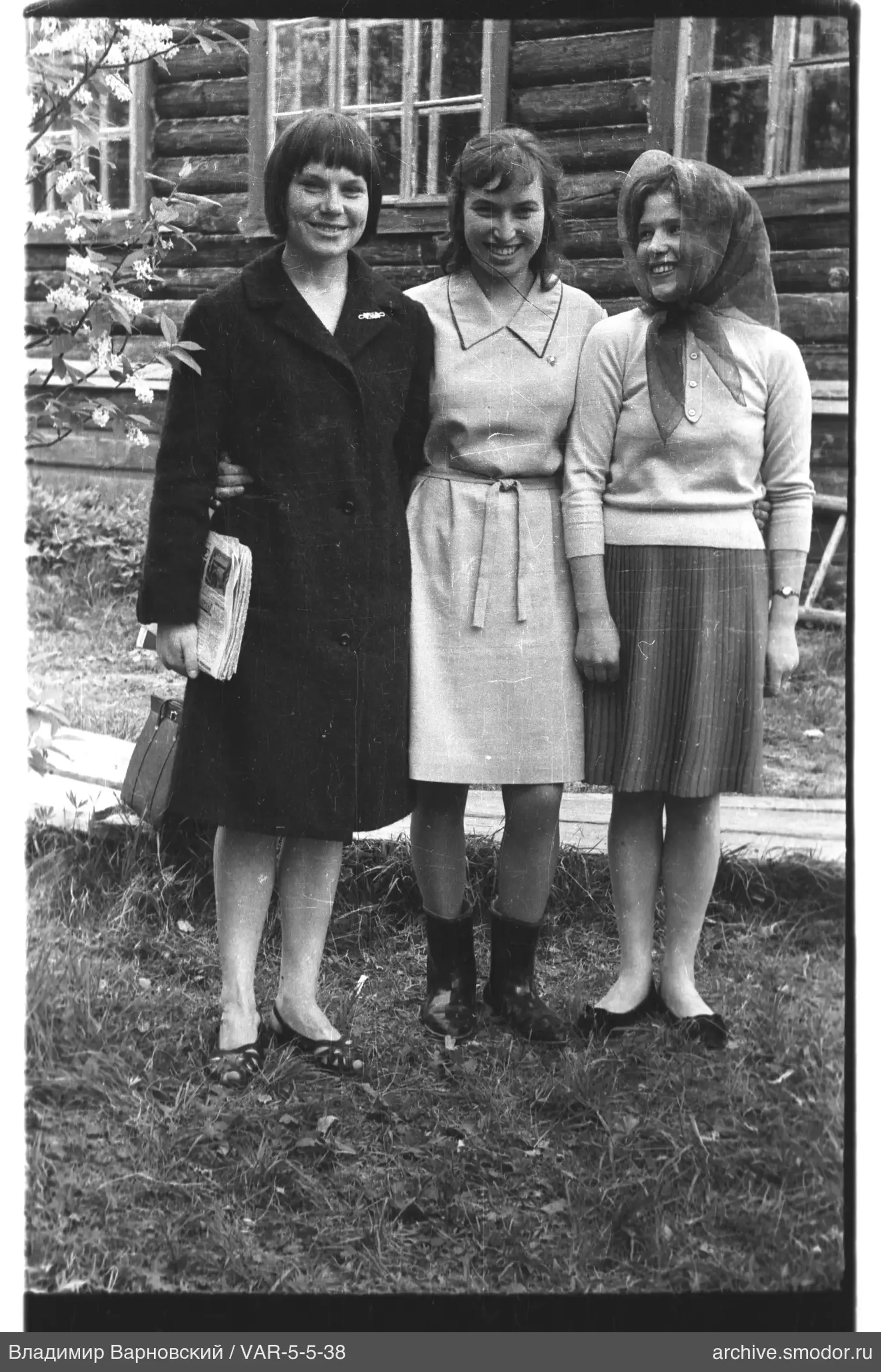 Gruppenporträt von Frauen vor einem Holzhaus auf dem Gras