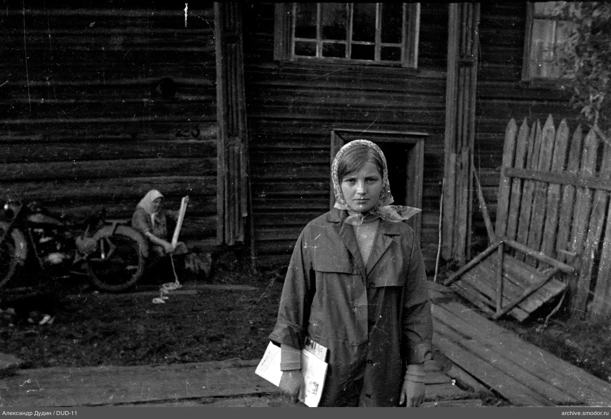 Женщина с бумагами у деревянного здания