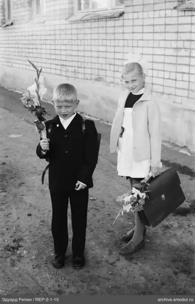 Gruppe von Kindern mit Blumen und Rucksäcken