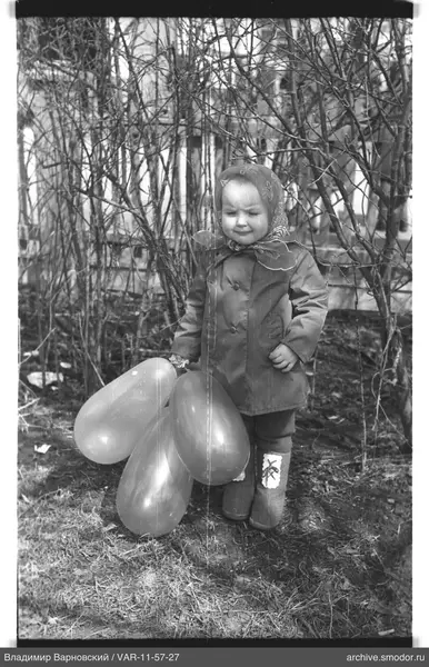 Kind mit Ballons bei Büschen