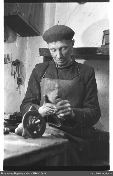 Man polishing mechanical part at table