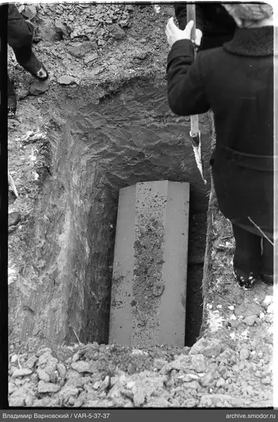 Grave with closed coffin and participants