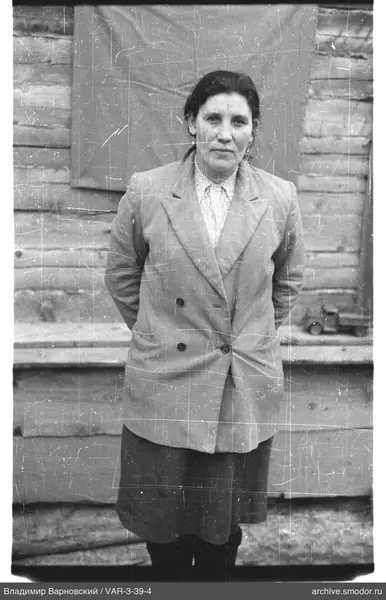 Frau in hellem Outfit vor Holzwand