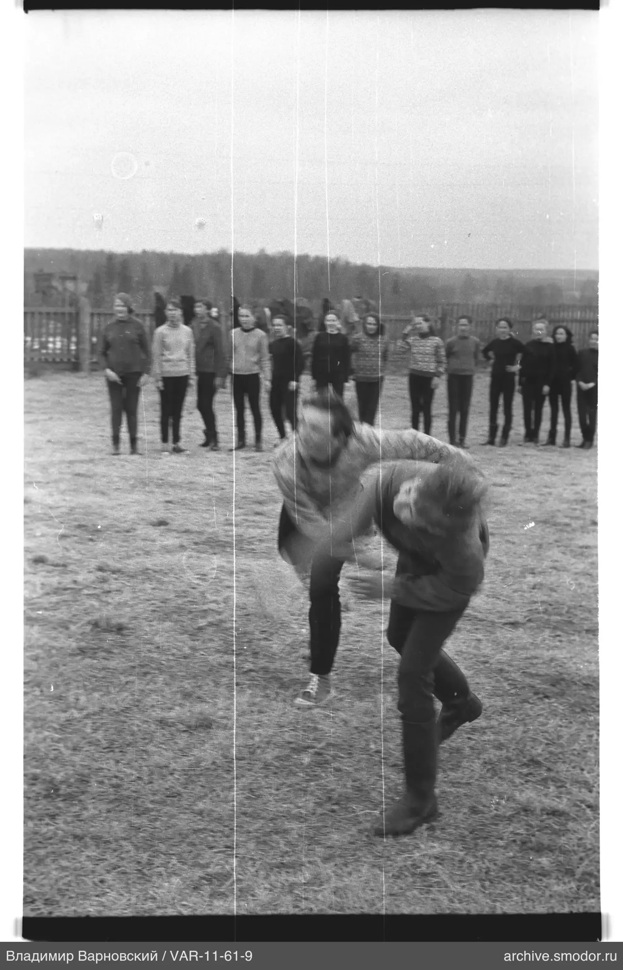 Two men in motion and group in field