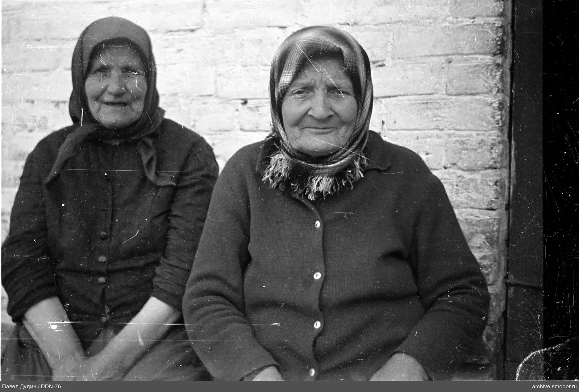 Две пожилые женщины на скамейке у стены