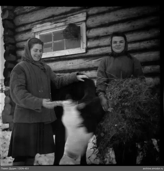 Zwei Frauen mit Kuh am Holzhaus