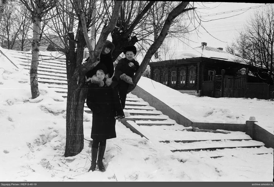 Frau und Kinder am Baum im Winter